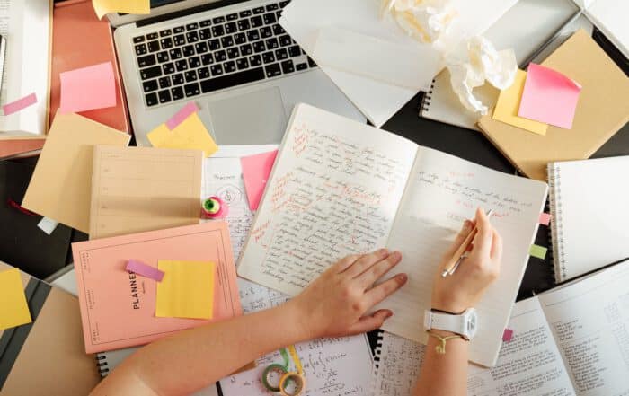 Schreibtisch mit Lernnotizen, Notizbuch und Laptop bei der Prüfungsvorbereitung