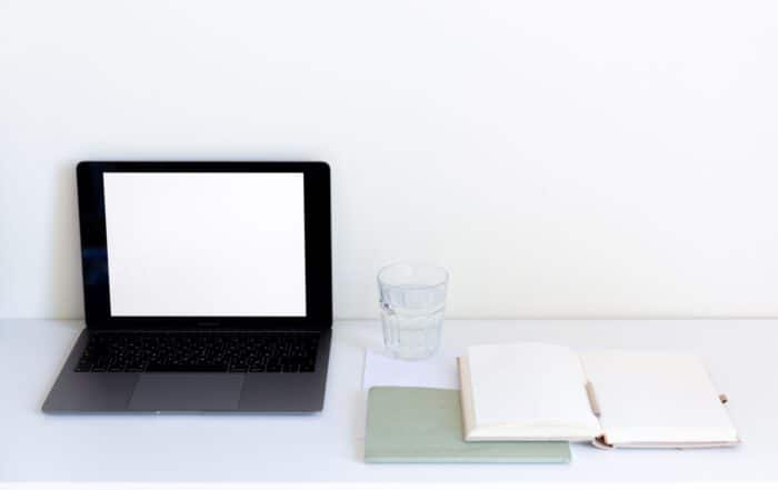 Aufgeräumter Schreibtisch mit Laptop und aufgeschlagenem Notizbuch zum Start in die Selbstständigkeit
